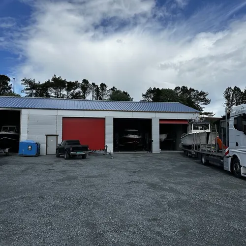 Hallen sett forfra med portene åpne og båter inne, en lastebil med båt står til høyre