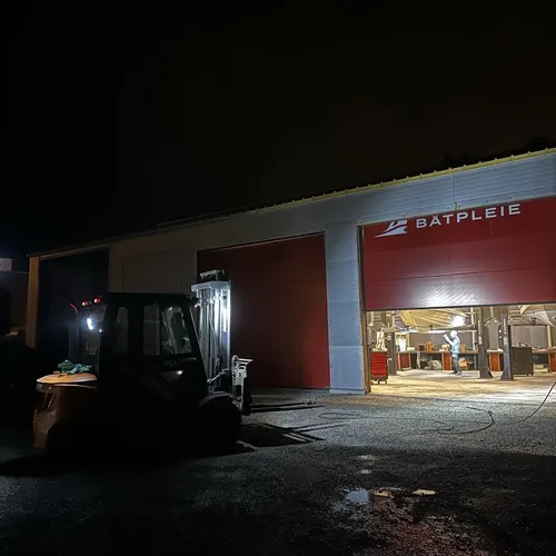 Hallen om kvelden med lys i porten og logoen på veggen, en truck står utenfor
