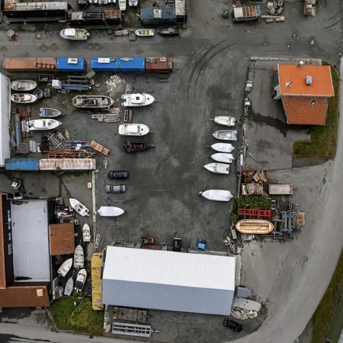Dronebilde av plassen med båter oppstilt i rader rundt hallen